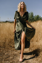Model walking in the dark olive velvet wrap dress, highlighting skirt movement, lining coverage, and flattering wrap fit.