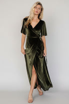Side profile of the dark olive Katelyn Velvet Maxi Wrap Dress highlighting the wrap waist tie, tulip skirt overlap, and gentle fabric drape.