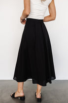 Studio shot of the Katie pleated midi skirt in black on a mannequin or model, emphasizing pleat definition, high-rise waist and tailored finish.