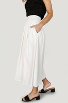 Back view of off-white pleated skirt highlighting the discreet back zipper, pleat fall, and finished hem at midi length.