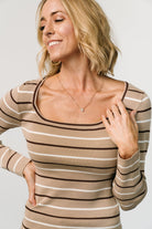 Side profile of Kaylee taupe stripe top on model, highlighting fitted long sleeves and close-fitting knit texture with subtle neutral stripes.