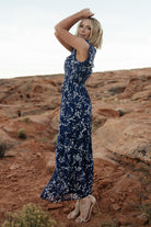 Detail shot of short flutter sleeve and ruffle trim on the blue floral chiffon dress, capturing fabric movement and pattern.