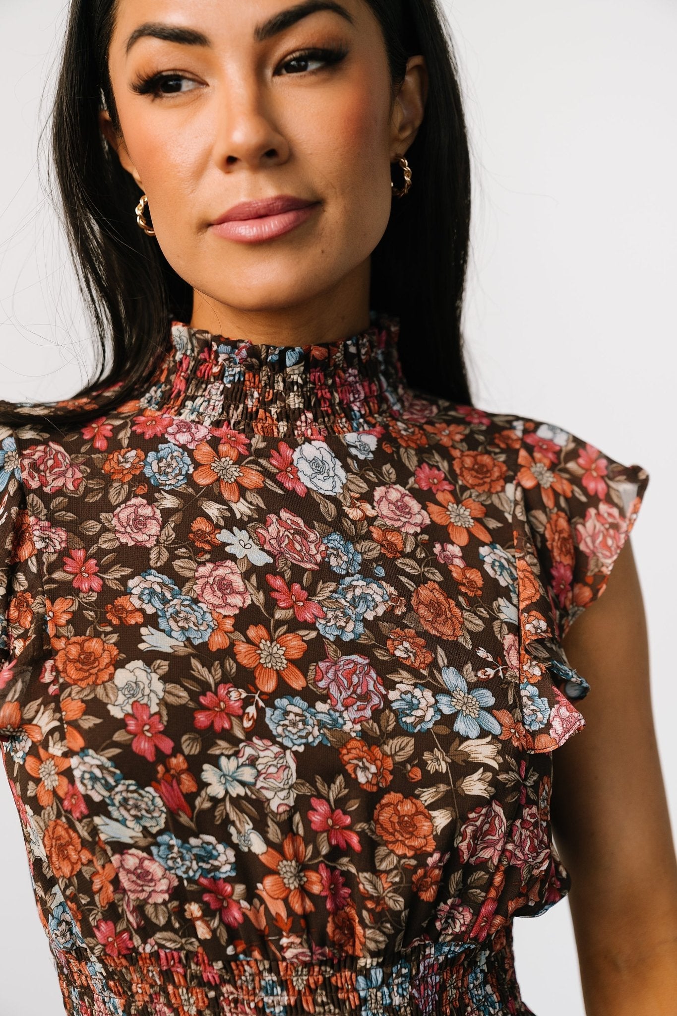 Close-up of smocked neckline and ruffle detailing on the brown multi floral print, illustrating fabric texture and stitching.