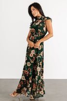 Detail shot of fabric and print pattern on dark green floral chiffon dress showing color contrast of orange, beige, and light green blooms.