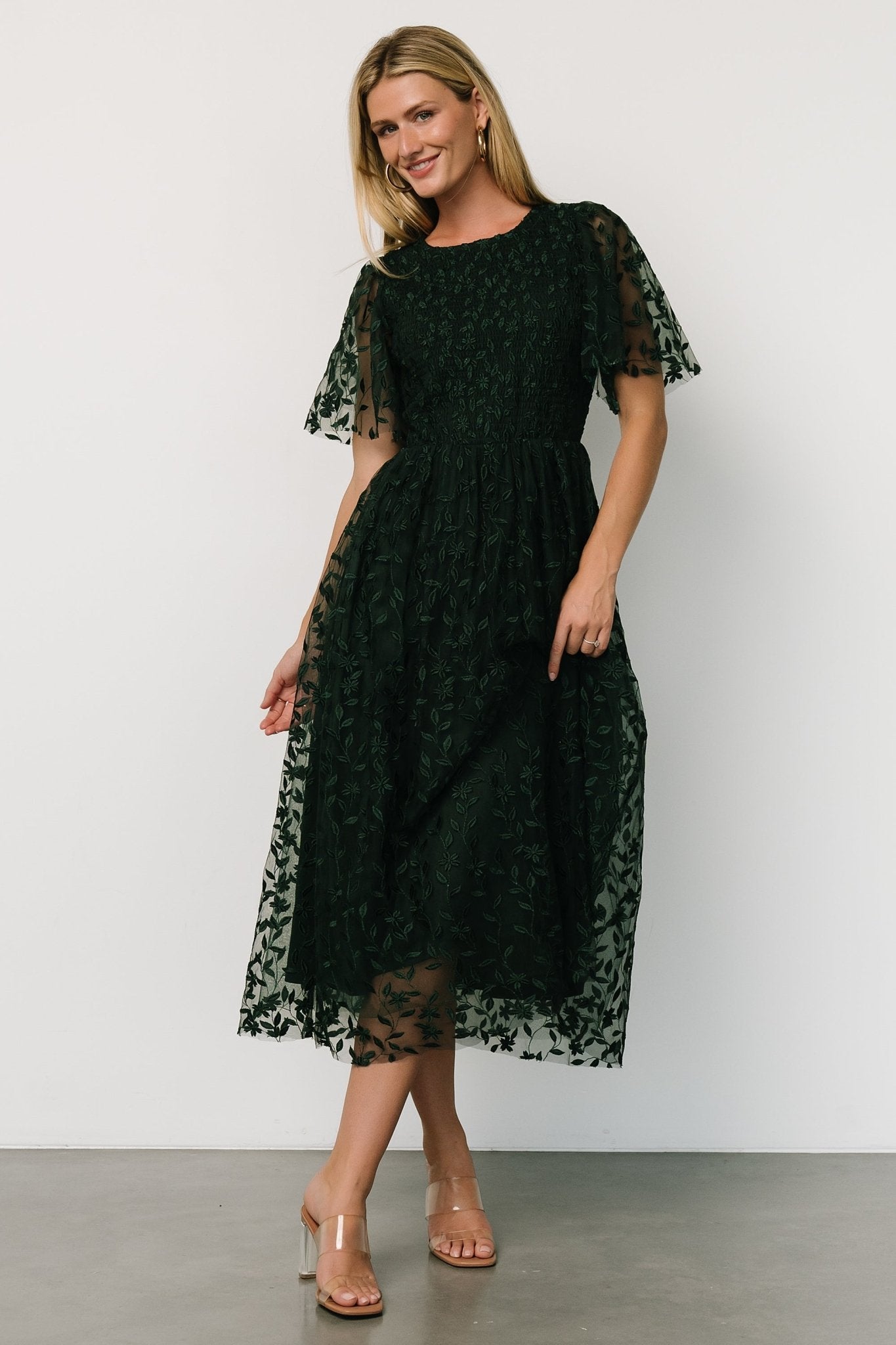 Side profile of Kendra dress showing subtle gathered waist and the layered tulle skirt movement in deep green fabric.