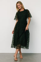 Side profile of Kendra dress showing subtle gathered waist and the layered tulle skirt movement in deep green fabric.