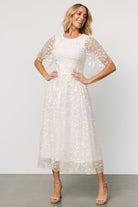 Back view showing single-button keyhole closure and smocked bodice on white Kendra embroidered midi dress in tulle.