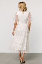 Model wearing Kendra white midi dress, showing flutter sleeve movement and natural gathered waist, flattering silhouette.
