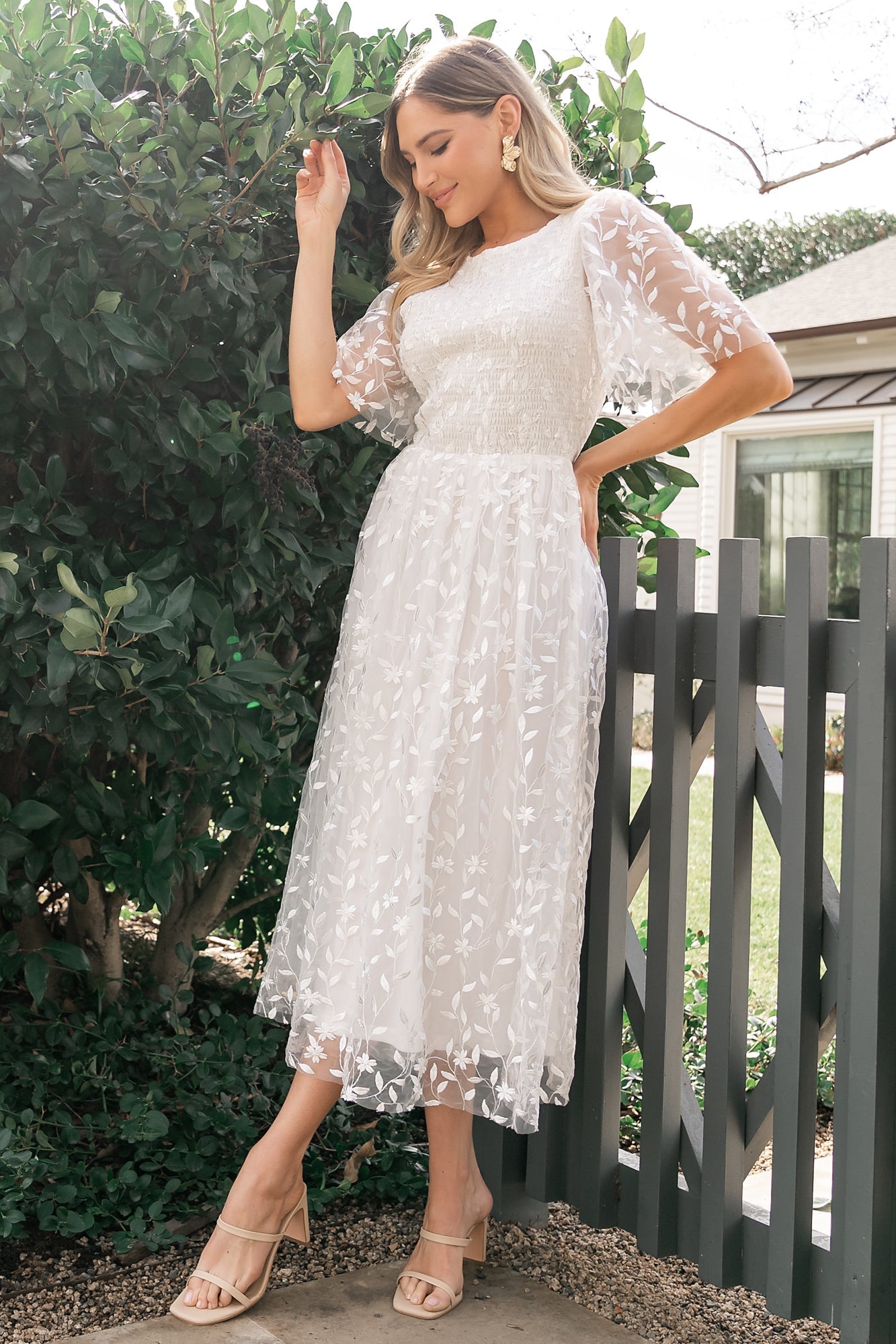 Side profile of Kendra embroidered white midi dress highlighting midi skirt length and subtle gathering at the natural waist.