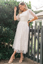 Side profile of Kendra embroidered white midi dress highlighting midi skirt length and subtle gathering at the natural waist.
