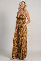 Close-up of the Khloe jumpsuit fabric pattern showing deep jade florals on a rich gold satin-like background and subtle fabric sheen.