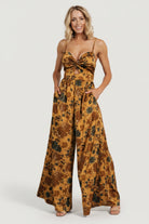 Front view of model wearing Khloe wide-leg jumpsuit in gold multi floral print, showing the sweetheart neckline and flowing palazzo silhouette.