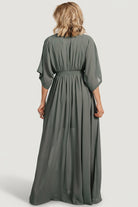 Back view of dark sage Kia kimono maxi dress on model, showing full maxi length, gentle train and unlined sleeves.