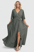 Model wearing dark sage Kia kimono maxi dress with self-tie sash visible at elastic waistband, styled for occasion wear.