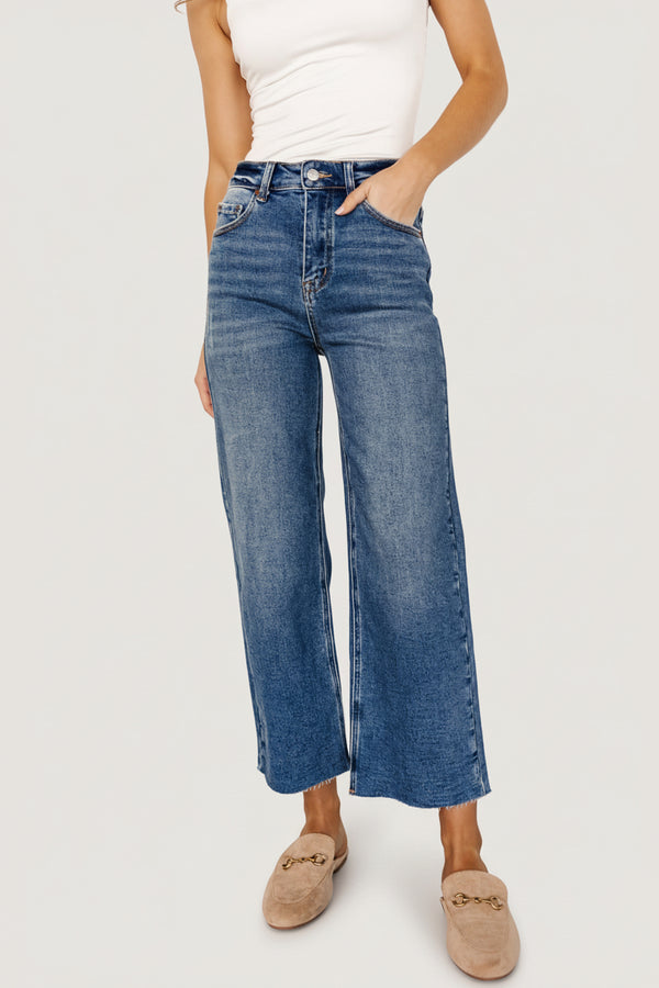 Front view of Kirby high-rise wide-leg jeans in medium blue wash, showing cropped raw hem and distressed pocket detail.