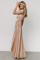 Model walking in the Krystal champagne wrap gown, tulip skirt opening and drape visible, demonstrating movement and elegant silhouette for events.