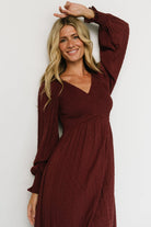 Back view of Lainey smocked dotted midi in mulberry showing smocked back bodice, elasticized waist detail, and lined skirt hem.