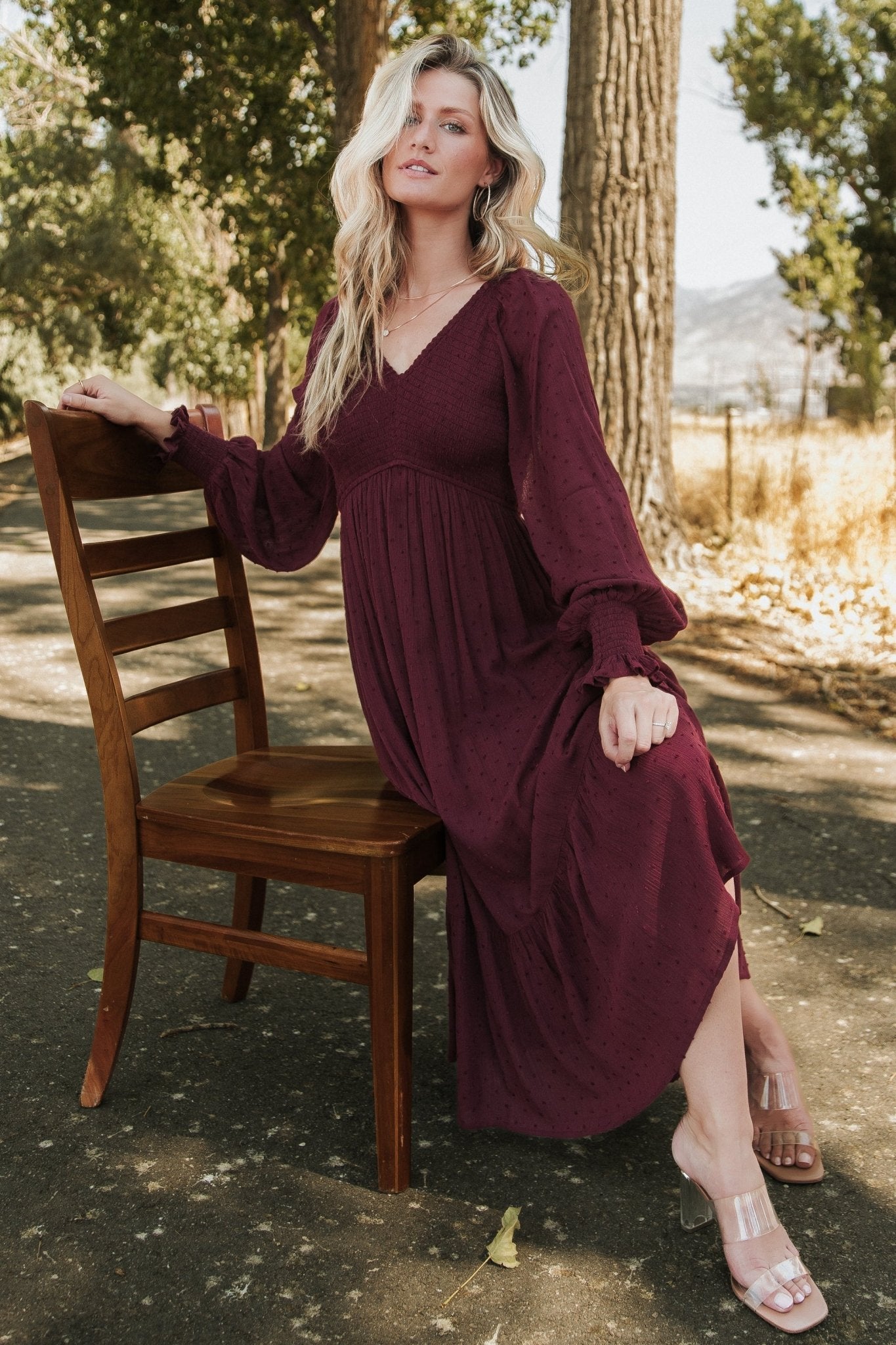 Model wearing Lainey mulberry midi dress, angled view highlighting smocked bodice, elastic shoulders, sleeve cuffs, and relaxed skirt movement.
