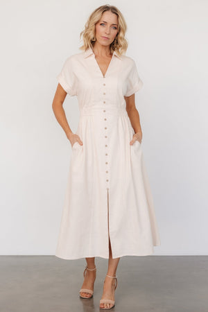 Front view of natural linen-cotton midi dress with collared V-neckline, faux button placket, front slit and smocked shaping at the waist, shown on a model.