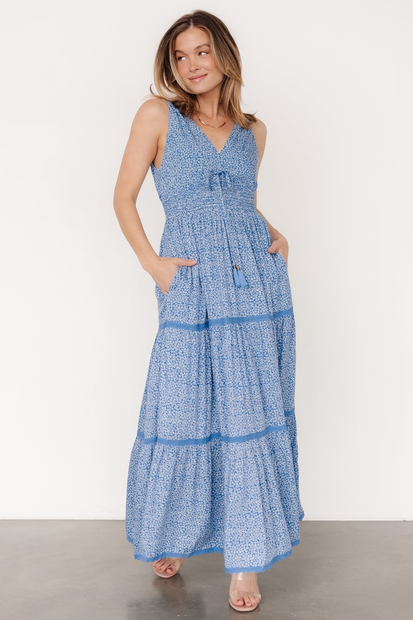 Front view of blue floral rayon maxi dress showing V-neckline, tank straps, lace tiers and a flowing full-length skirt with delicate off-white flowers.