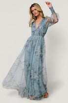 Styled outfit photo of dusty blue floral tulle maxi dress with accessories, highlighting versatility for events and maternity wear.