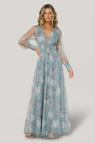 Front view of Layla tulle maxi dress in light blue floral with deep V-neck, smocked waist, long sheer sleeves, and flowing skirt, styled on model.