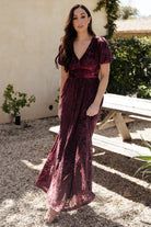 Back view of the embossed velvet maxi dress in Mulberry, showing sleeve shape, back drape and full coverage lining.