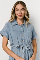 Back view of denim midi dress highlighting the tiered A-line skirt and diagonal seam details for movement.