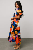 Back view of rust and navy multi Lola midi dress, showing back silhouette and skirt flow.
