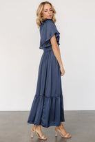 Close-up of smocked bodice and flutter sleeve showing stretch detail and rounded V neckline in deep midnight blue fabric.