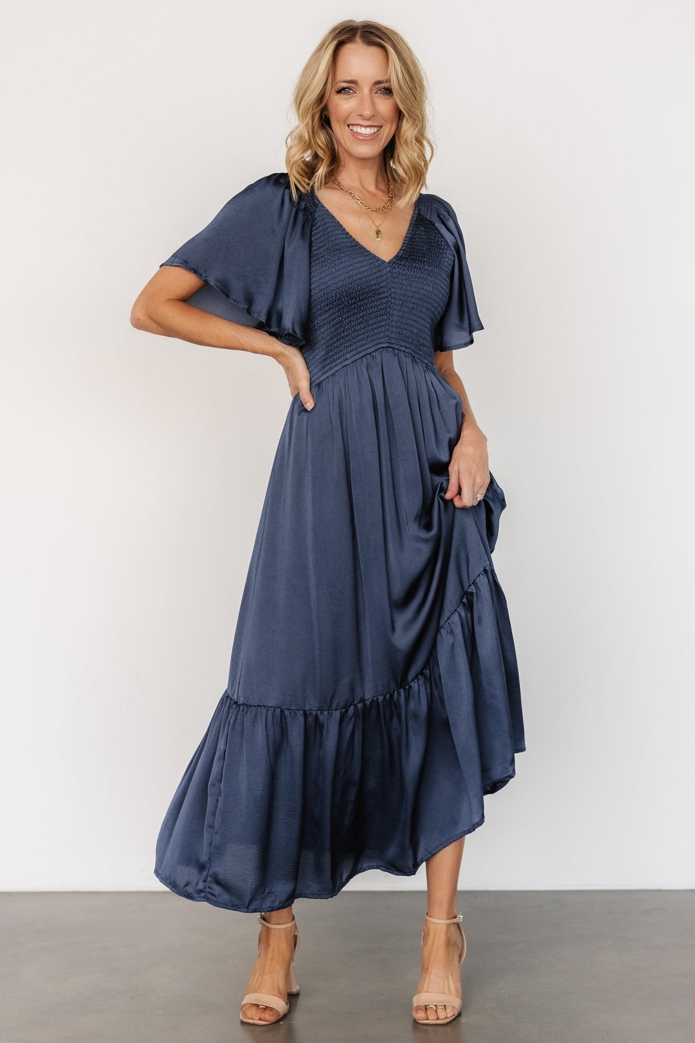 Styled flatlay of the Lovell Smocked Midi Dress in midnight blue with accessories to show outfit pairing possibilities.