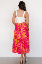 Model wearing Luana tiered midi skirt in orange and fuchsia, showing side seam pockets and midi length with sandals.