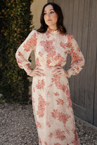 Three-quarter view of beige and rose Luciana maxi dress on model, highlighting flowing chiffon, elastic back waist, and single-tier skirt movement.