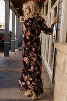 Back view highlighting the keyhole with double-button closure and elasticized back waist on the black and mauve floral maxi.