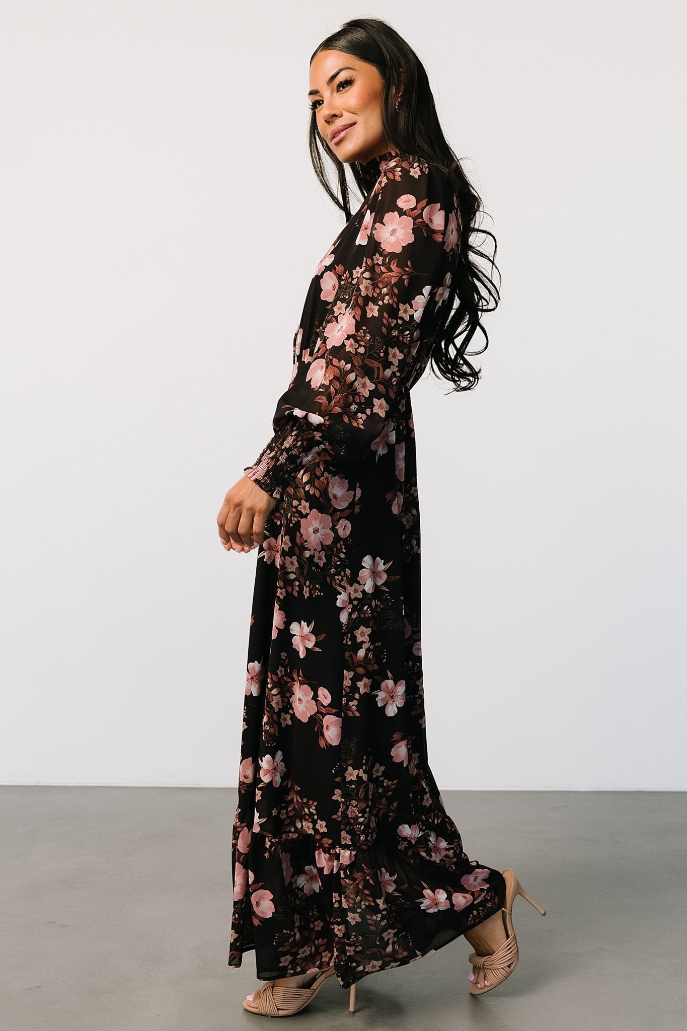 Close-up of smocked high neckline and ruffle cuff detail on the lightweight chiffon fabric with floral print.