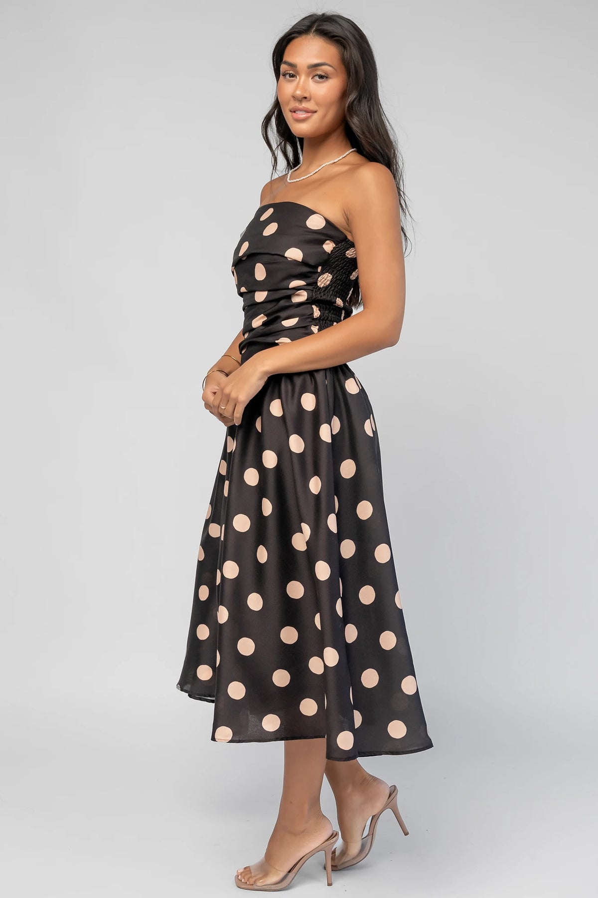 Lucienne Strapless Midi Dress in Black + Beige Dot with strapless neckline, cinched bodice, smocked back, and dropped waist.