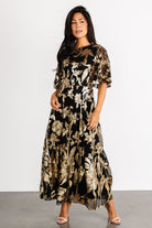Front view of Lucy Sequin Dress in black tulle with gold sequin floral embroidery, fitted elastic waist and flowing maxi-length skirt, shown on model.