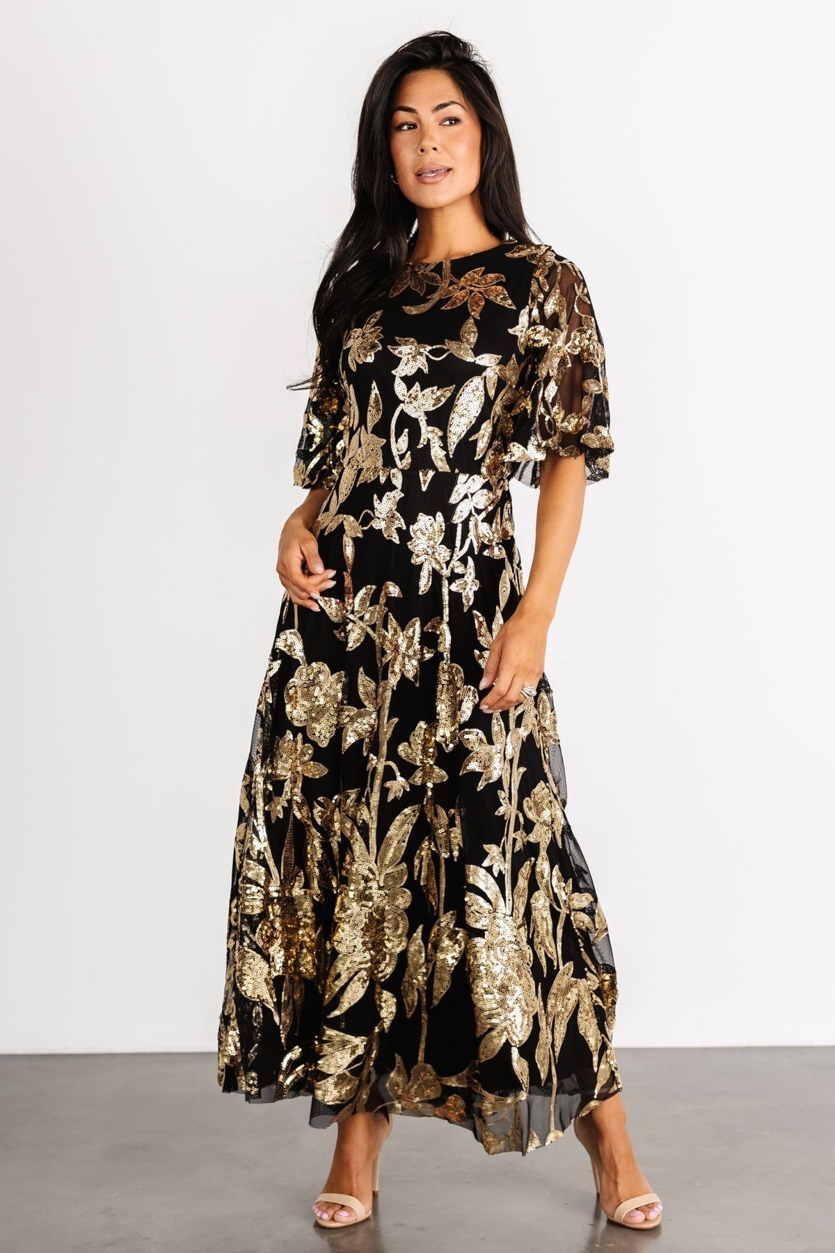 Front view of Lucy Sequin Dress in black tulle with gold sequin floral embroidery, fitted elastic waist and flowing maxi-length skirt, shown on model.