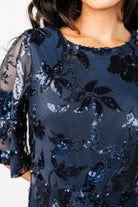 Close-up of the dress bodice showing dense navy floral sequins on tulle overlay with smooth lined fabric beneath for coverage.