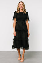 Close-up of Lysandra Smocked Dot Dress in black highlighting smocked bodice, polka-dot tulle overlay, and delicate ruffle trim at neckline and sleeves.
