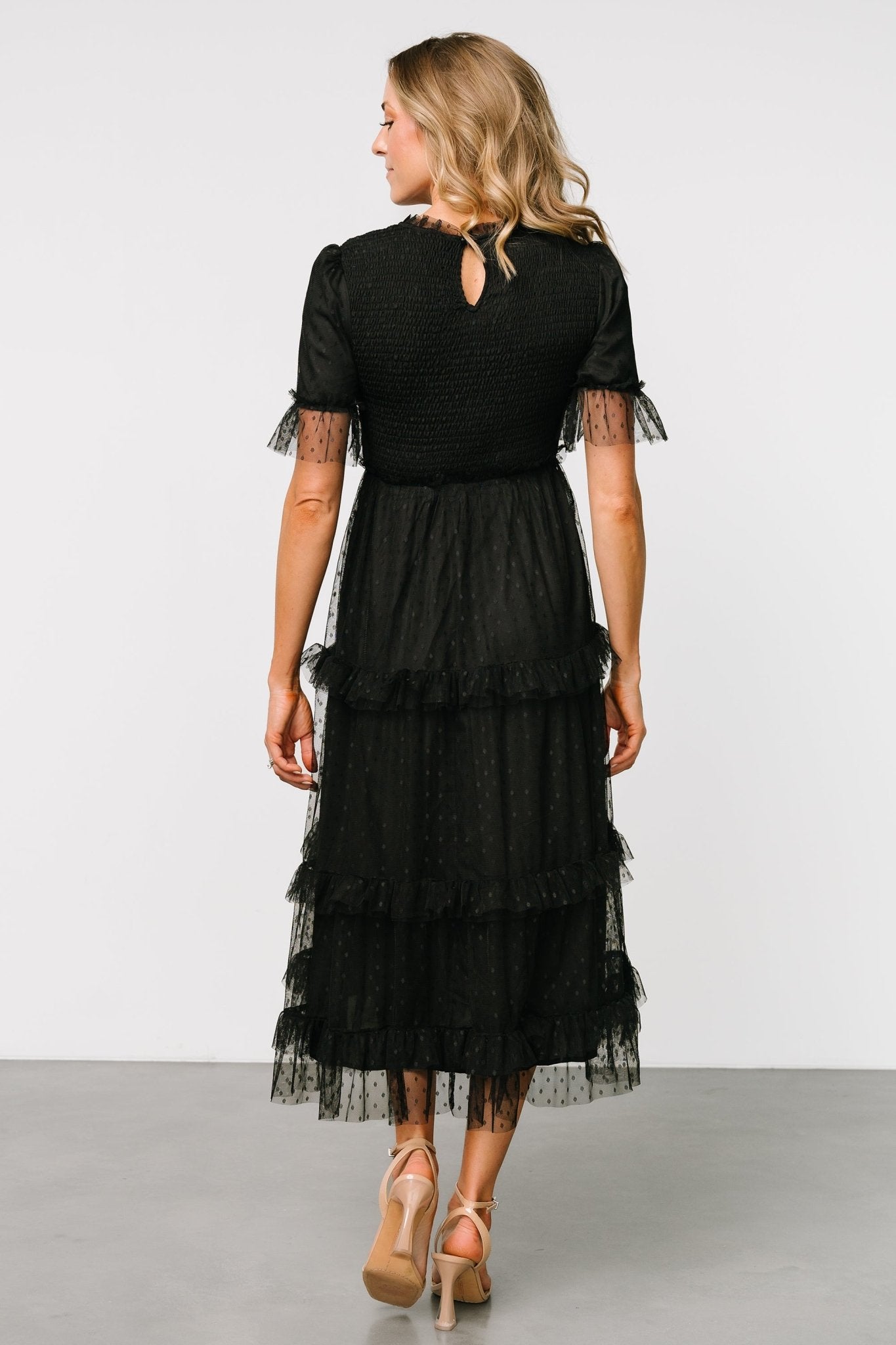 Back view of the black Lysandra Smocked Dot Dress showing keyhole and button closure, layered tulle, and the dress’s tiered silhouette.