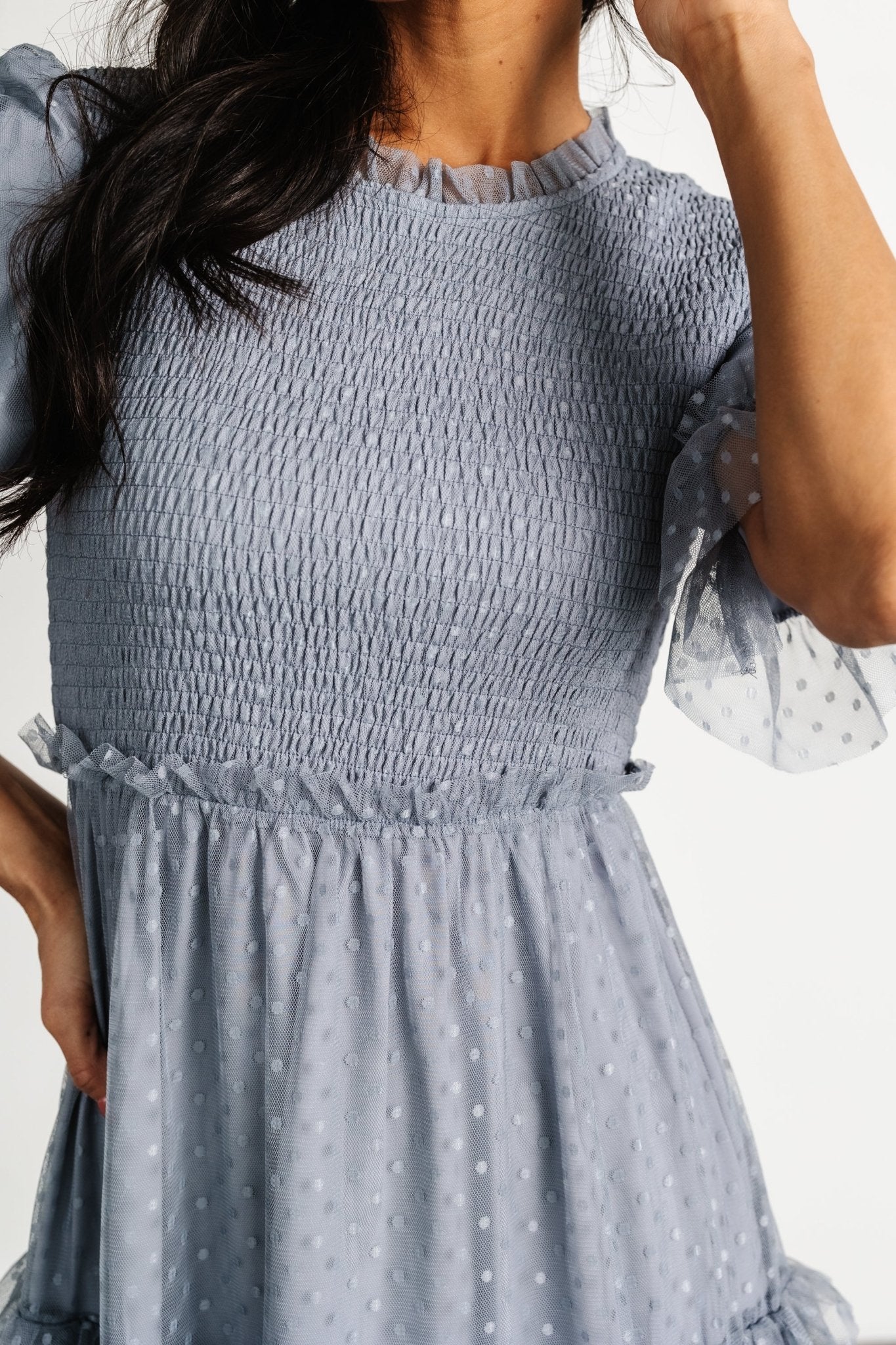 Three-quarter angle of Lysandra dress highlighting polka dot tulle overlay, short ruffle sleeves, and the flowing, tiered midi skirt with delicate ruffle edges.