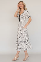 Back view of dress highlighting smocked back, elastic ruffled sleeve hems, and the single-tiered skirt silhouette in cream and black floral.