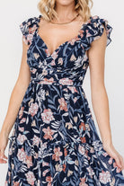 Full-length side view of Martina Maxi Dress in navy multi floral chiffon, highlighting flutter sleeves, tiered skirt movement, and maxi silhouette.