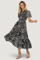 Side view of Mirabel dress showing hidden side pocket, elastic waist detail, and tiered midi skirt with ruffle trims.