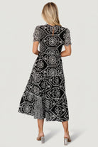 Studio shot of Mirabel midi dress on mannequin, displaying layered scalloped sleeves, high ruffled neckline and full embroidered pattern.