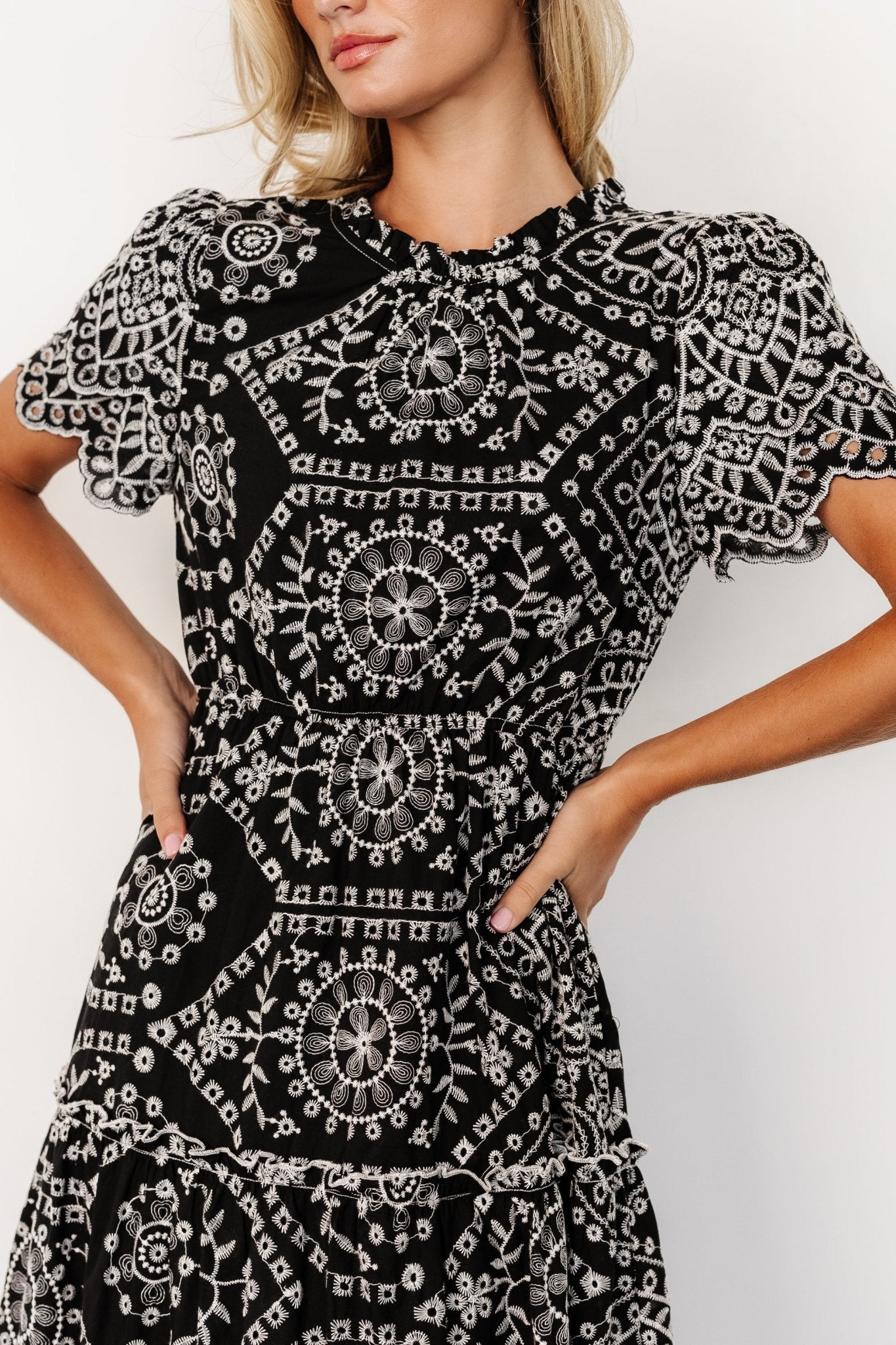 Back detail of Mirabel midi dress showing button keyhole closure, gathered elastic waist and tiered skirt with ruffle accents in black and white.