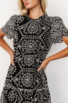 Back detail of Mirabel midi dress showing button keyhole closure, gathered elastic waist and tiered skirt with ruffle accents in black and white.