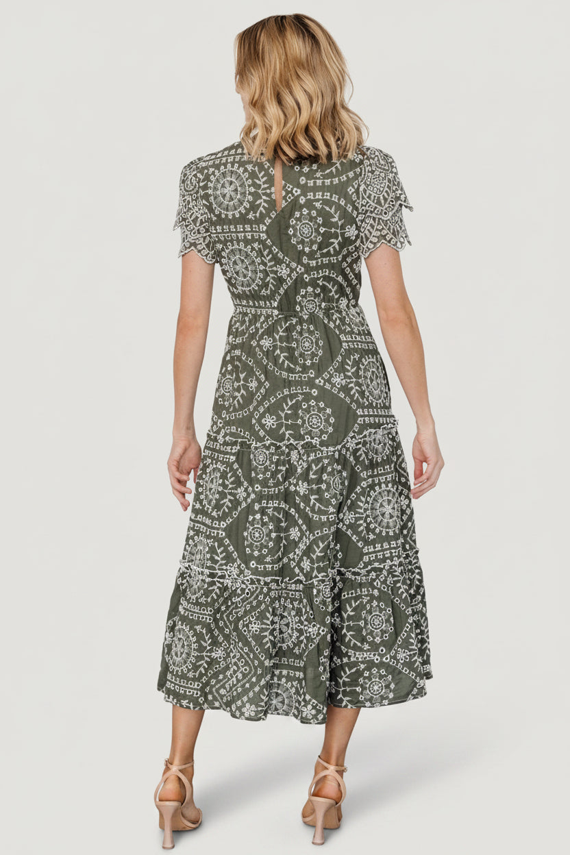Detail of hidden side pocket, cotton fabric texture, and ruffle trim at a seam on the Mirabel Eyelet Midi Dress in olive and white.
