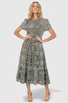Front view of Mirabel Eyelet Midi Dress in olive and white showing embroidered eyelet, ruffle neckline, and tiered skirt.